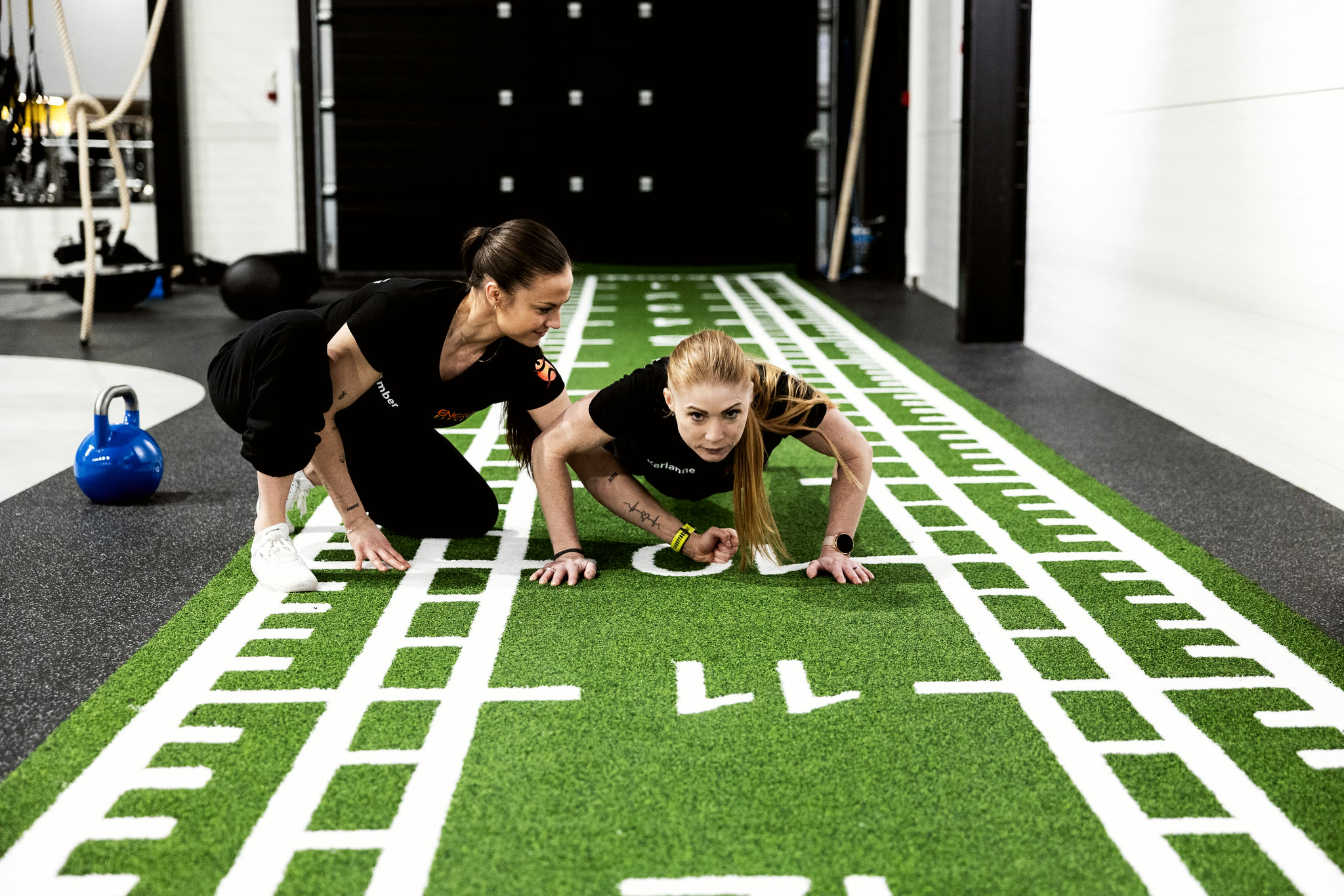 Personlig trener veileder push-ups på kunstgresset hos ENERGY Fitness